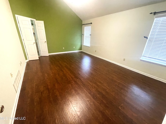 empty room with baseboards, visible vents, wood finished floors, and high vaulted ceiling