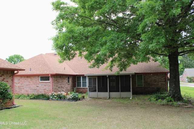 rear view of house featuring a yard, brick siding, a sunroom, and roof with shingles