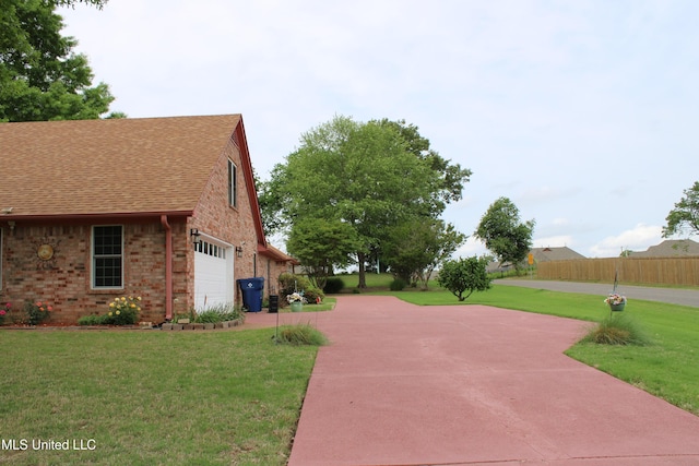 exterior space with roof with shingles, fence, a yard, and brick siding