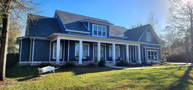 view of front of house featuring covered porch, a front yard, and roof with shingles