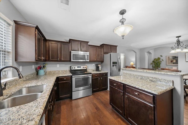 kitchen featuring stainless steel appliances, a sink, a center island, dark wood-style flooring, and dark brown cabinets