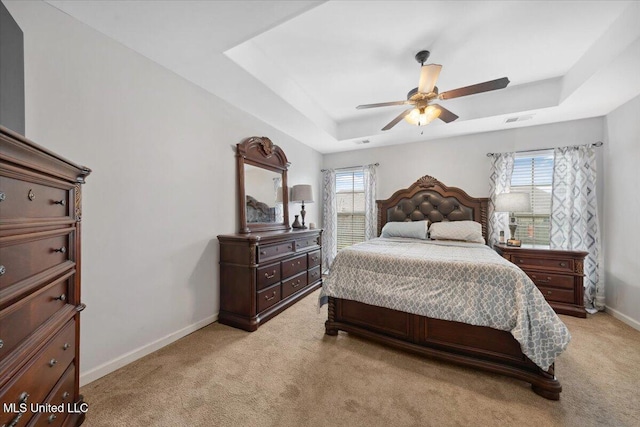 bedroom with a raised ceiling, multiple windows, and baseboards