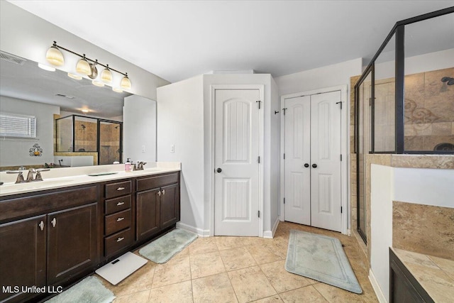 bathroom with a shower stall, double vanity, and tile patterned floors