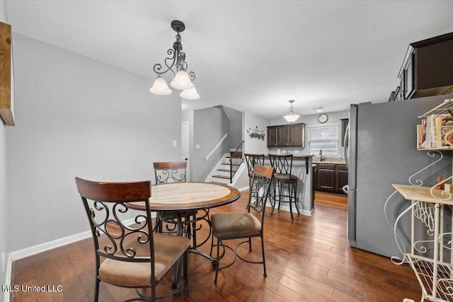 dining space featuring dark wood finished floors, stairs, baseboards, and a chandelier