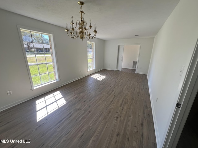 unfurnished dining area featuring a wealth of natural light, dark hardwood / wood-style flooring, and an inviting chandelier