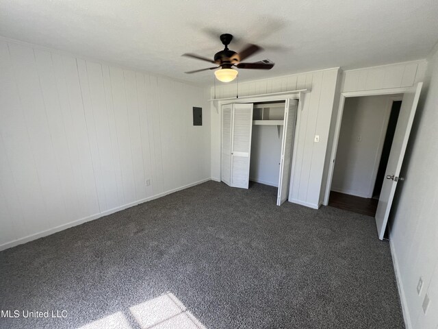 unfurnished bedroom with electric panel, ceiling fan, a closet, and dark colored carpet