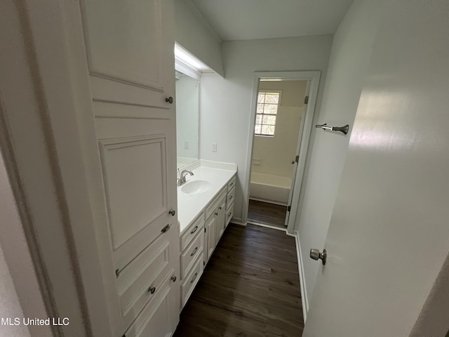 bathroom featuring hardwood / wood-style flooring, vanity, and a tub