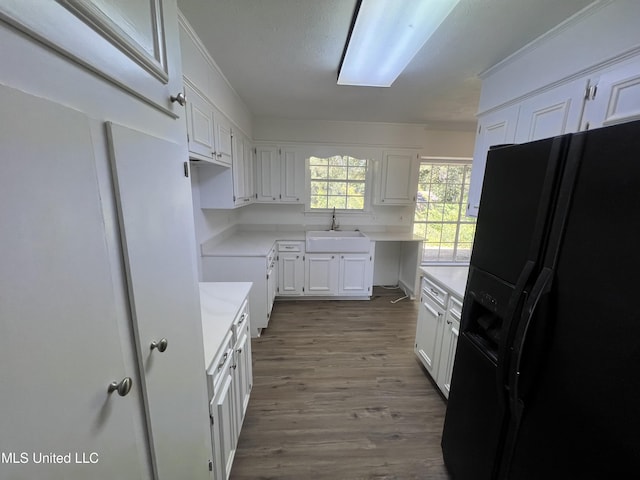 kitchen with white cabinets, hardwood / wood-style flooring, sink, and black refrigerator with ice dispenser