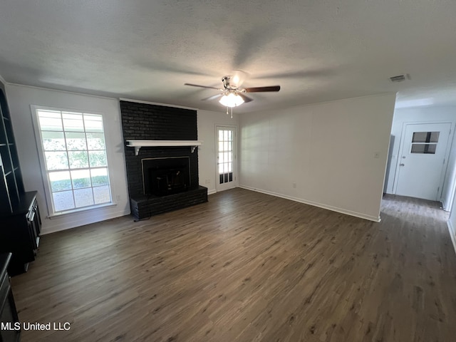 unfurnished living room with dark hardwood / wood-style floors, ceiling fan, a textured ceiling, and a brick fireplace