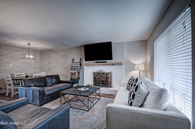 living room with an inviting chandelier, wood finished floors, and a brick fireplace