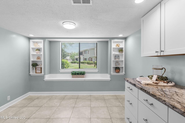 dining space featuring baseboards, light tile patterned flooring, a textured ceiling, and visible vents