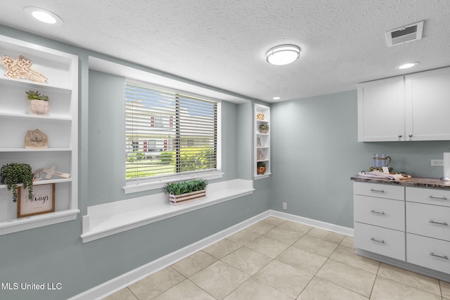 dining space featuring baseboards, a textured ceiling, light tile patterned flooring, and visible vents