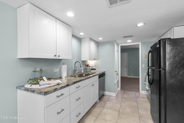 kitchen with a sink, stainless steel dishwasher, freestanding refrigerator, and visible vents