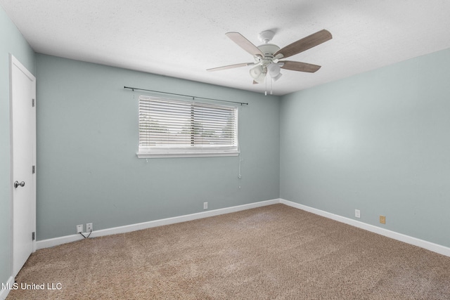 carpeted empty room with baseboards and a ceiling fan