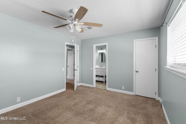 unfurnished bedroom featuring ceiling fan, a sink, ensuite bath, carpet, and baseboards
