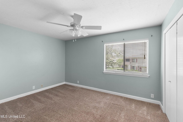 carpeted empty room featuring baseboards and a ceiling fan