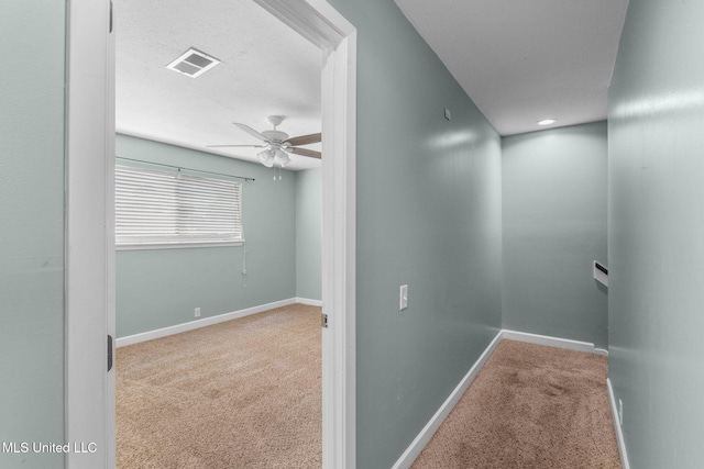 hallway with carpet floors, baseboards, visible vents, and an upstairs landing
