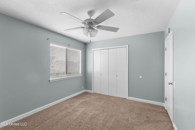 unfurnished bedroom featuring carpet flooring, a textured ceiling, a ceiling fan, baseboards, and a closet
