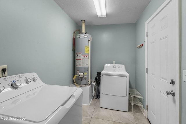 washroom with light tile patterned floors, gas water heater, washing machine and dryer, and laundry area