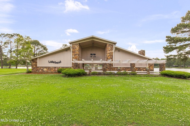 view of side of property featuring a lawn, a chimney, and stone siding