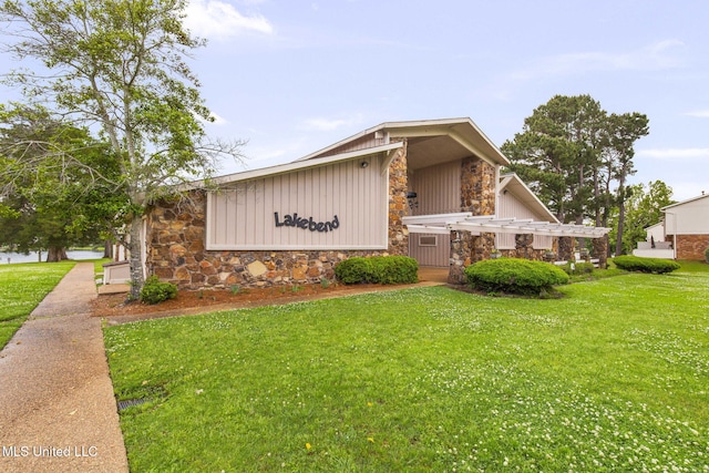 view of side of property featuring board and batten siding, a yard, and stone siding