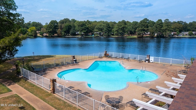 pool featuring fence, a patio, and a water view
