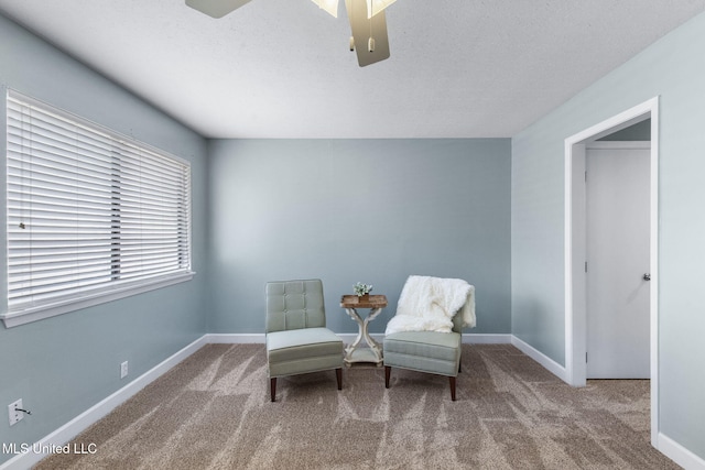 living area with baseboards, a ceiling fan, carpet flooring, and a textured ceiling