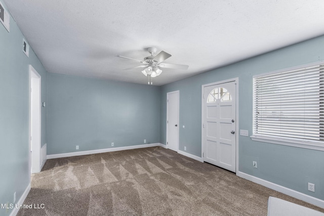carpeted spare room featuring baseboards, a ceiling fan, a textured ceiling, and visible vents