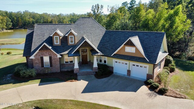 craftsman inspired home with a water view, a front yard, and a garage