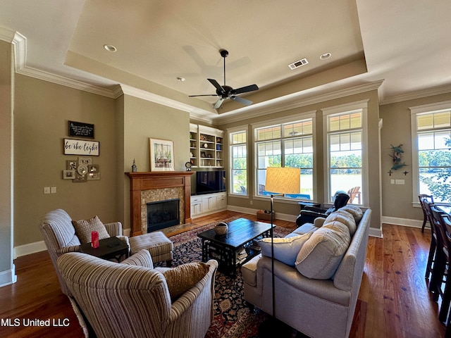 living room with a tray ceiling, plenty of natural light, and hardwood / wood-style floors