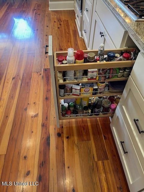 details with hardwood / wood-style flooring, stovetop, and white cabinets