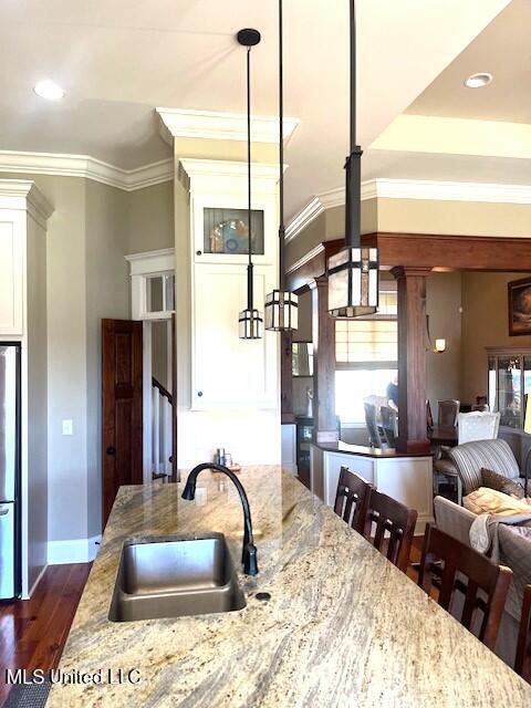 kitchen with light stone counters, dark hardwood / wood-style floors, sink, and decorative light fixtures