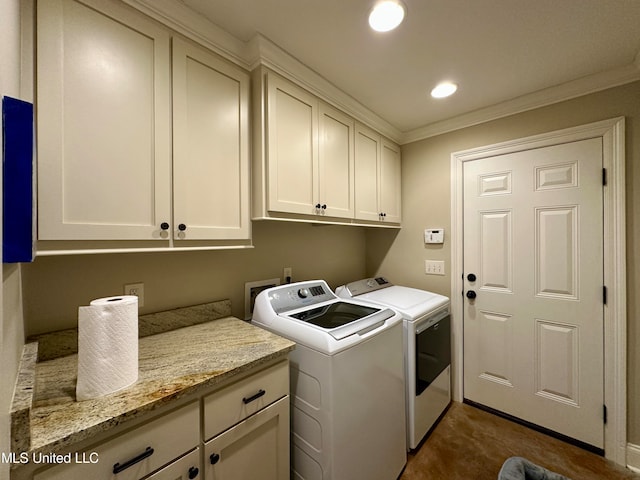 clothes washing area featuring washing machine and dryer, cabinets, and ornamental molding