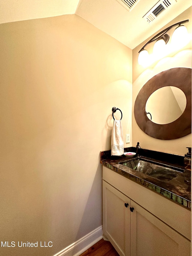 bathroom with vanity, wood-type flooring, and lofted ceiling