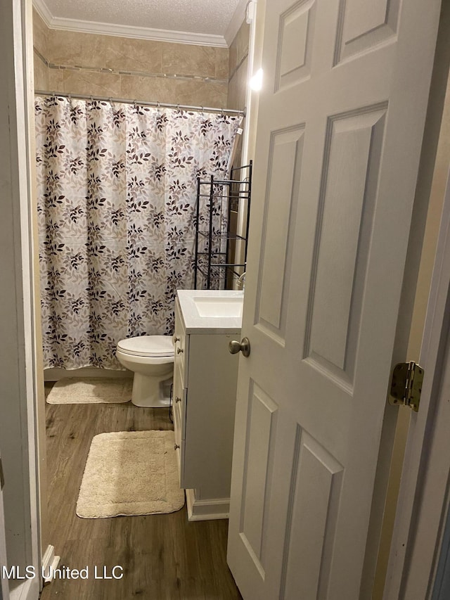 bathroom featuring vanity, toilet, ornamental molding, a textured ceiling, and wood-type flooring