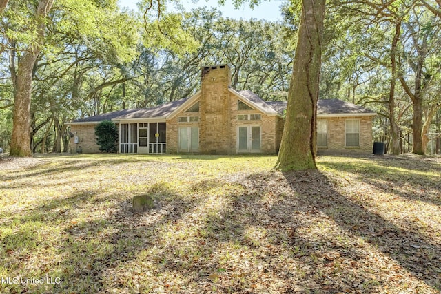 rear view of property with a yard and a sunroom