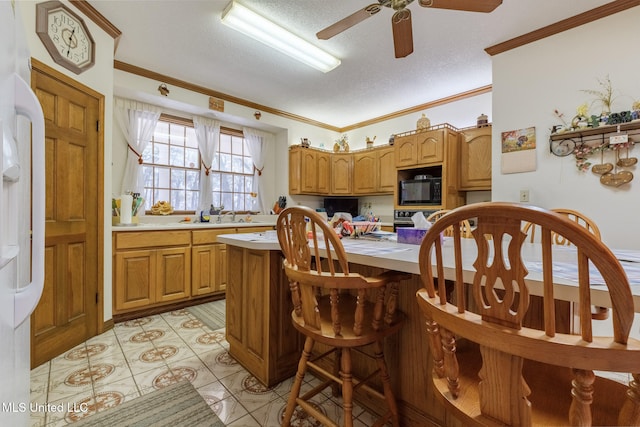 kitchen with a textured ceiling, black appliances, a kitchen breakfast bar, ornamental molding, and ceiling fan