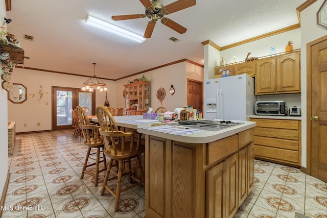 kitchen with hanging light fixtures, white fridge with ice dispenser, a textured ceiling, and a kitchen island