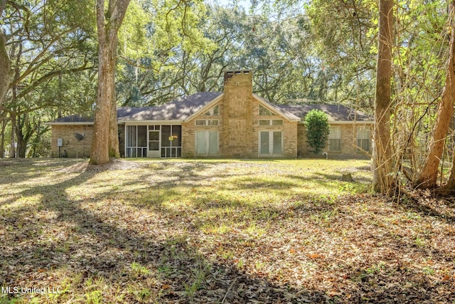 back of property featuring a sunroom, french doors, and a lawn