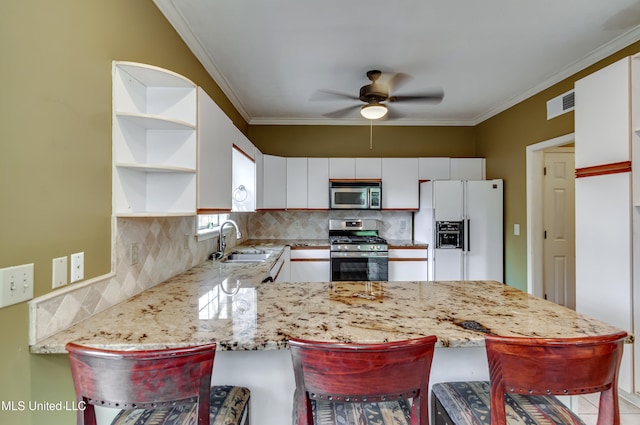 kitchen with appliances with stainless steel finishes, a breakfast bar, kitchen peninsula, and white cabinets