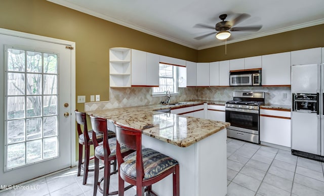 kitchen featuring kitchen peninsula, white cabinetry, a kitchen bar, a wealth of natural light, and stainless steel appliances