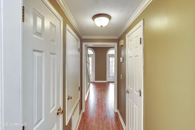 doorway to outside featuring crown molding, a textured ceiling, and light hardwood / wood-style floors