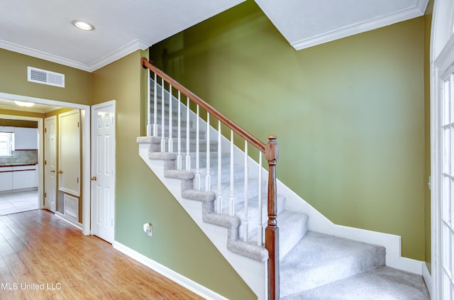 stairs featuring ornamental molding and hardwood / wood-style flooring