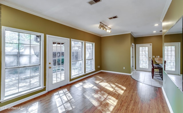 entryway with crown molding, light wood-type flooring, and plenty of natural light