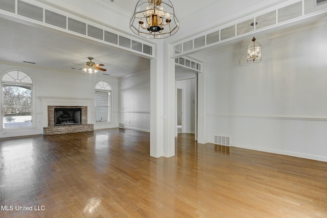 unfurnished living room featuring crown molding, ceiling fan with notable chandelier, and hardwood / wood-style flooring