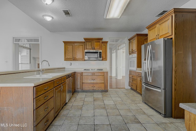 kitchen with light tile patterned floors, appliances with stainless steel finishes, sink, and a textured ceiling