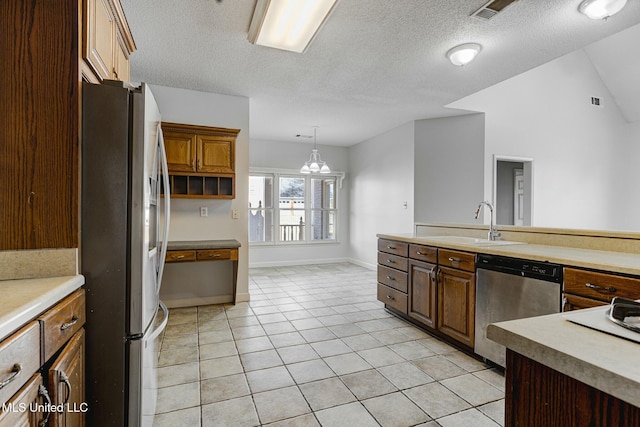 kitchen with appliances with stainless steel finishes, light tile patterned flooring, a textured ceiling, pendant lighting, and sink