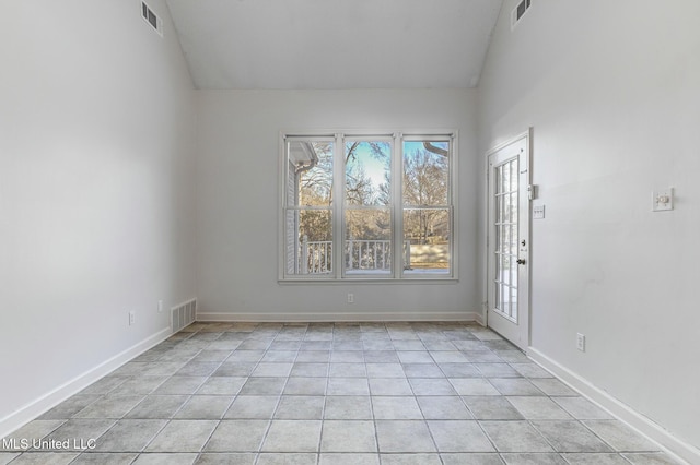 tiled spare room with vaulted ceiling