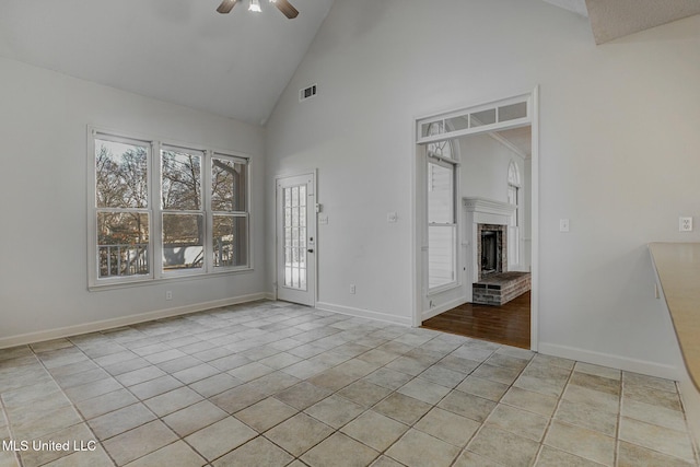 spare room with ceiling fan, light tile patterned flooring, a brick fireplace, and high vaulted ceiling