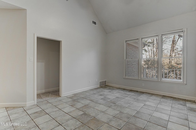 tiled spare room with high vaulted ceiling